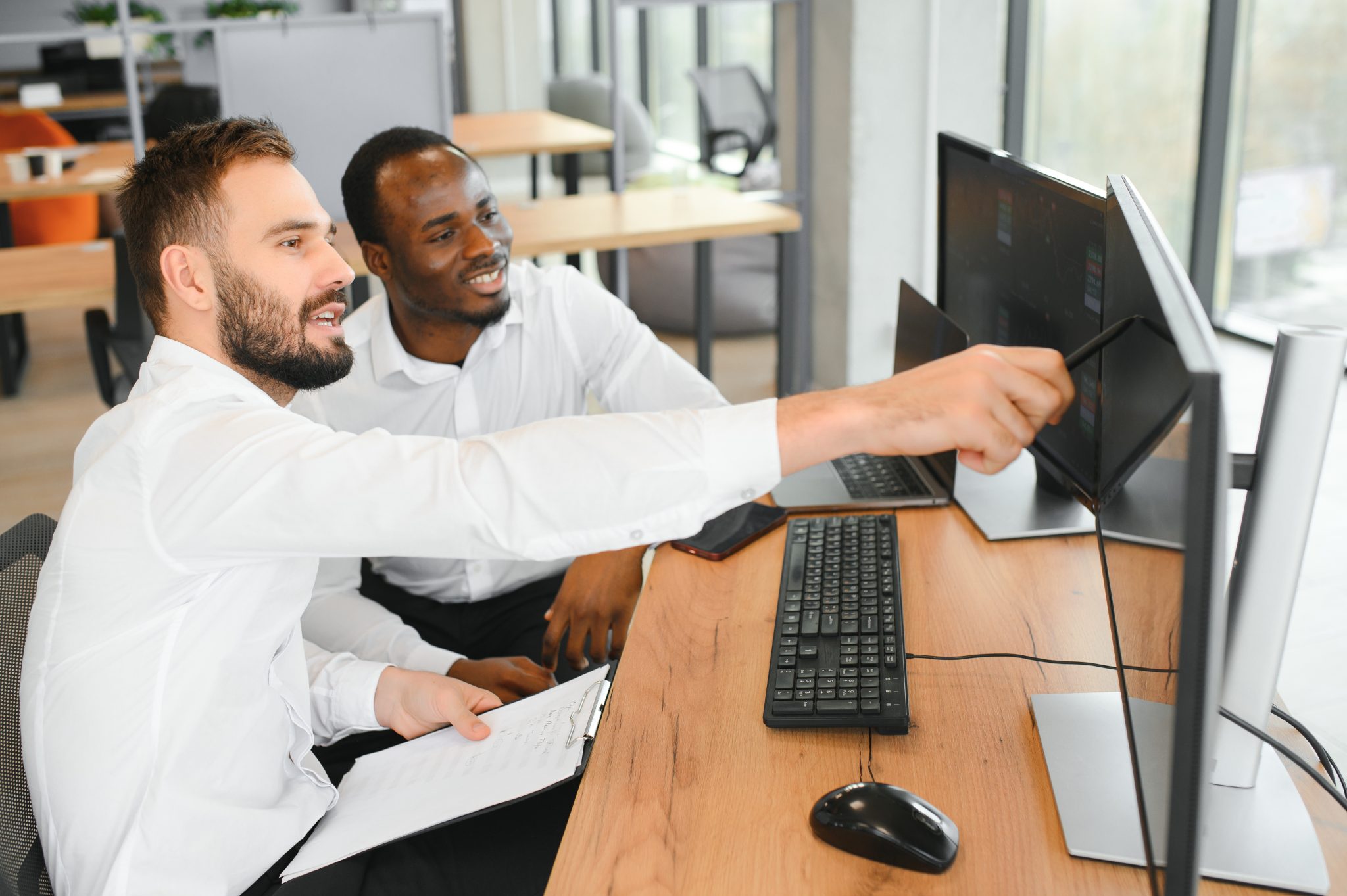 Two confident businessmen, financial analysts or investment advisers sitting at office desk