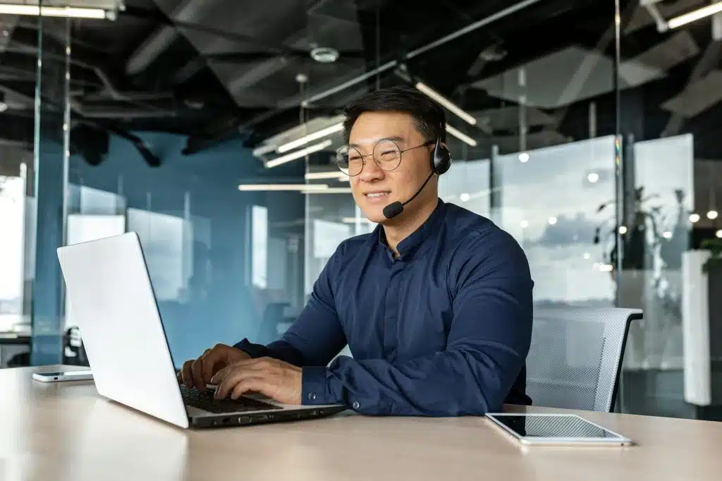 happy-and-smiling-worker-with-headset-for-video-call-asian-tech-support-man-talking-to-online-1024x682