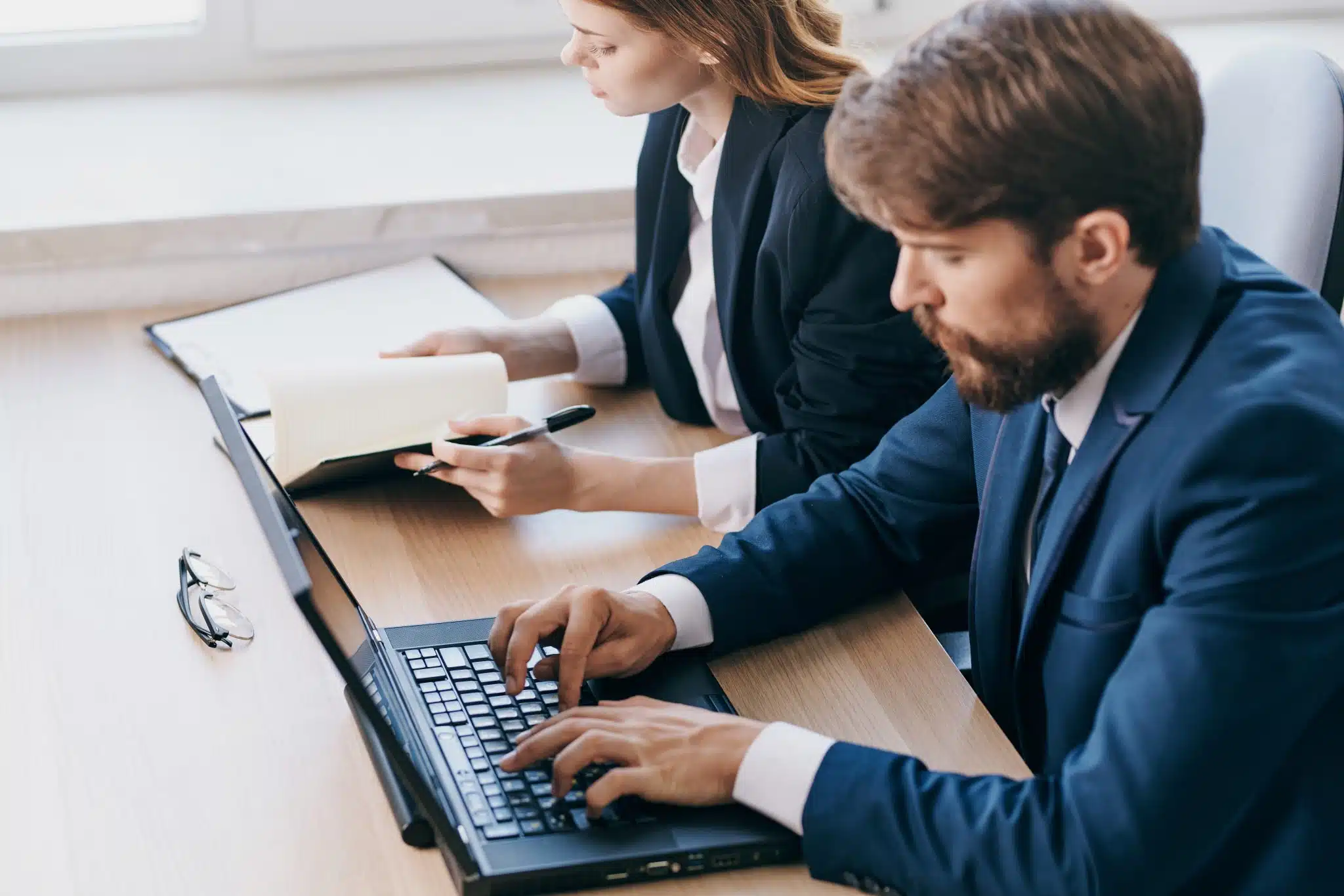 business-man-and-woman-sitting-at-a-desk-with-a-la-2023-11-27-04-53-18-utc-scaled